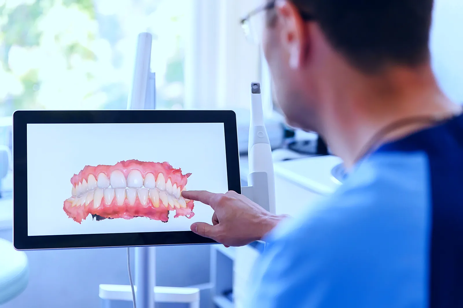 A man holding a tablet with a picture of a tooth on it.